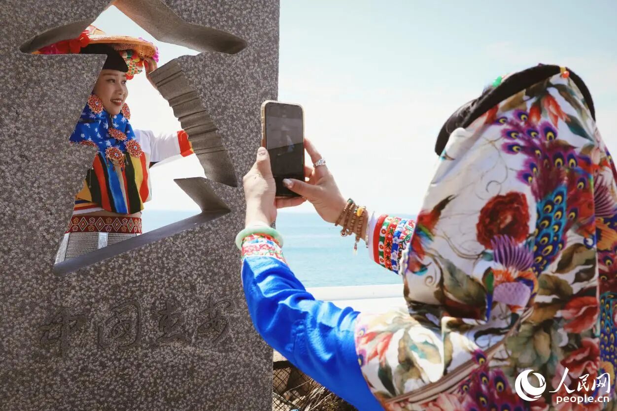 游客身著惠女服飾在海邊“打卡”。人民網(wǎng)記者 李唯一攝